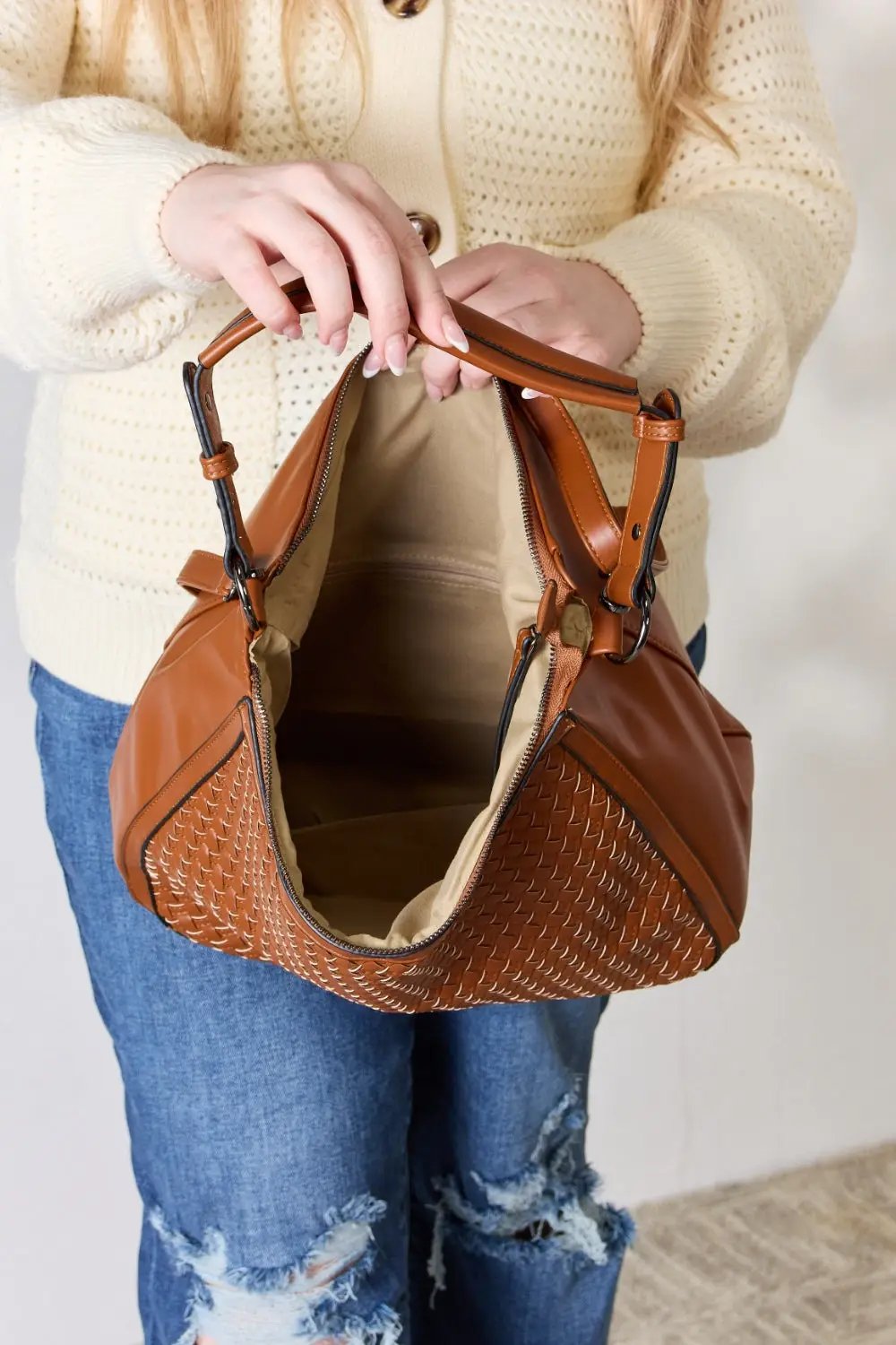 a woman holding a brown purse in her hand showing the inside of the purse